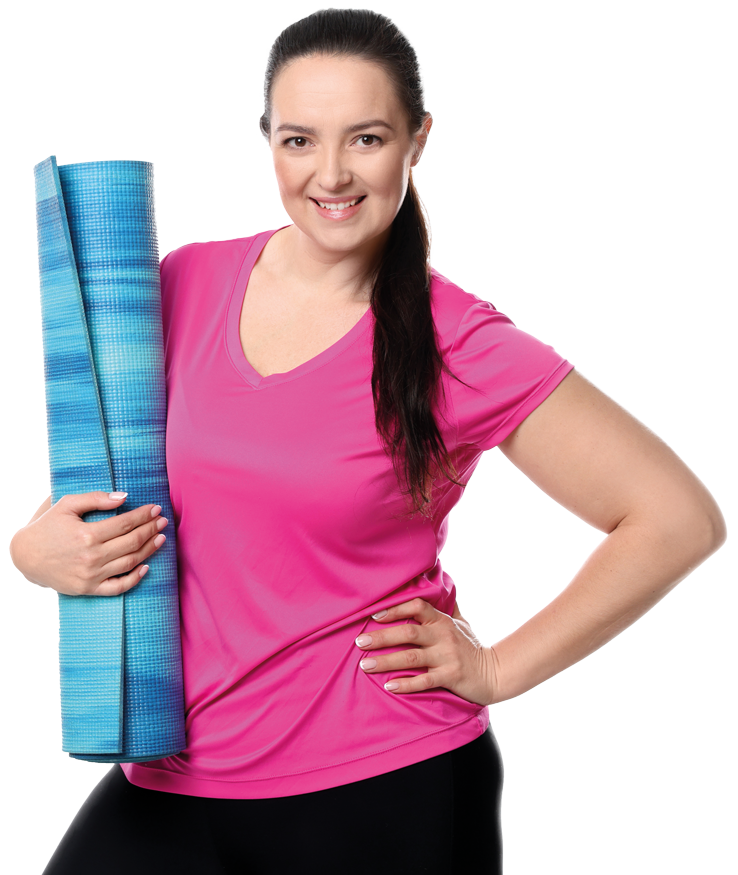 A happy middle aged woman with her hand on her hip, holding a yoga mat