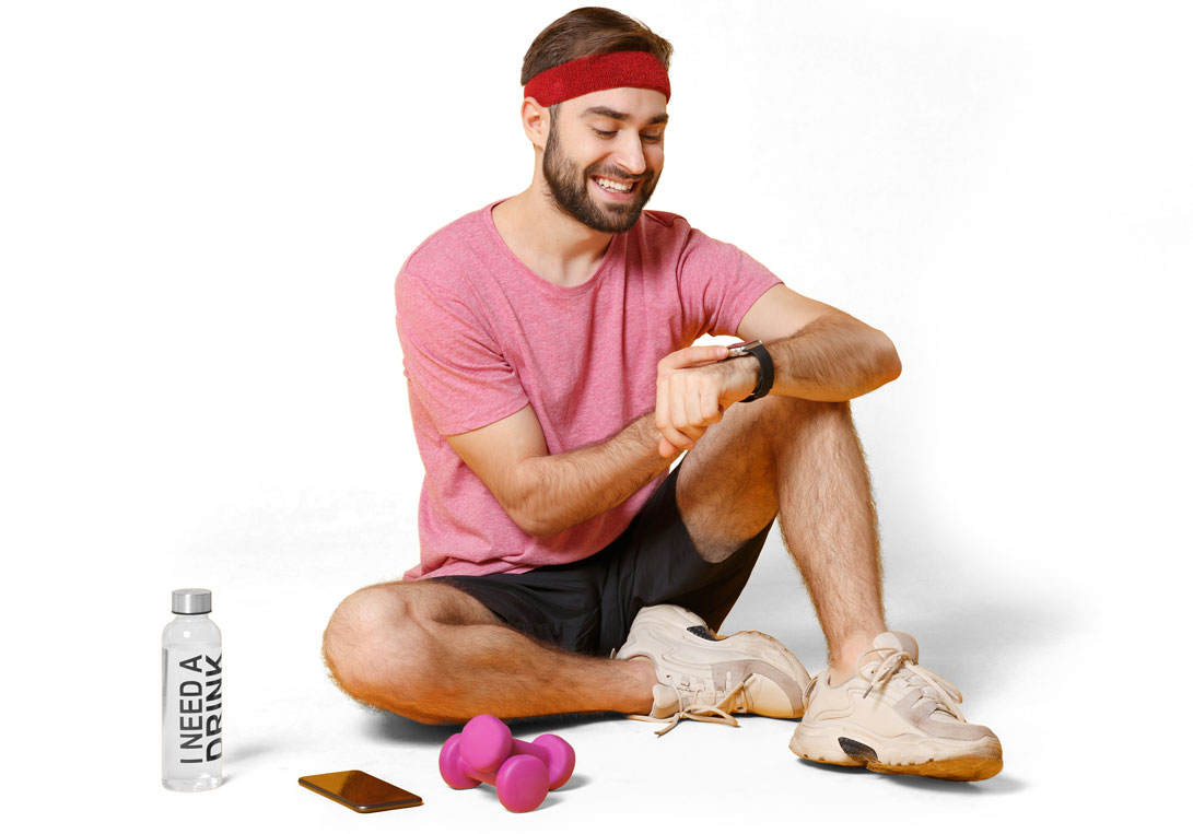 A young man in fitness clothes sitting on the floor and checking his heart rate